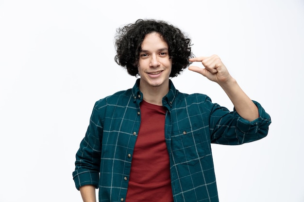 Smiling young handsome man looking at camera showing little amount gesture isolated on white background