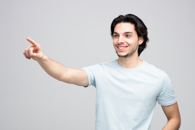 Smiling young handsome man looking and pointing at side isolated on white background