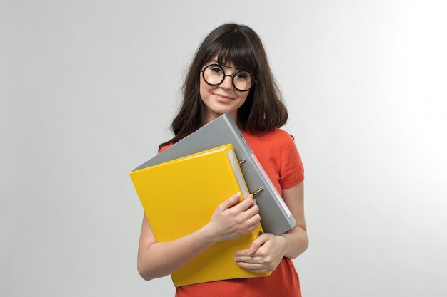 smiling young lady in designed t-shirt in good mood holding colored files with long hair on white