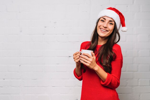 Smiling young lady in party hat with cup