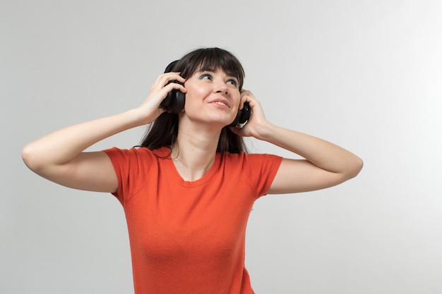 smiling young lady with earphones in designed t-shirt in good mood with long hair on white