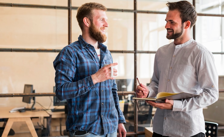 Free Photo smiling young male colleague looking each other