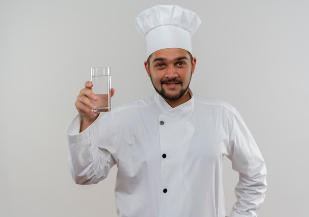 흰색 공간에 절연 물 잔을 들고 요리사 유니폼에 웃는 젊은 남성 요리사