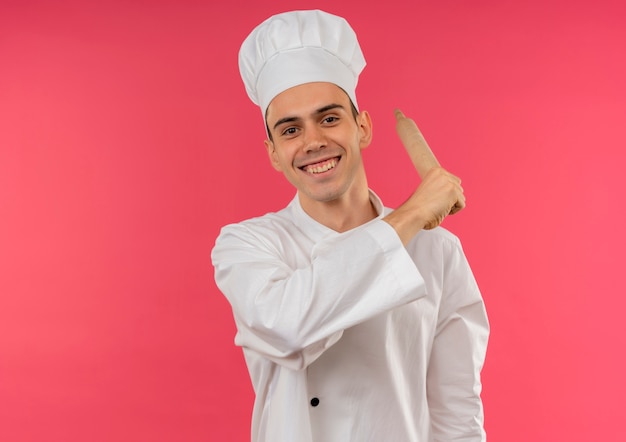 コピースペースで肩の周りに麺棒を保持しているシェフの制服を着て笑顔の若い男性料理人