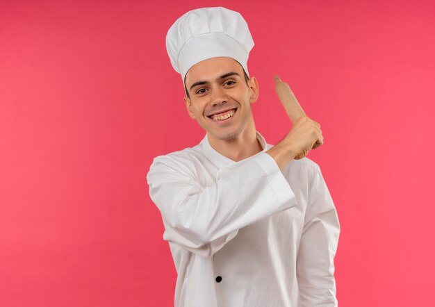 Smiling young male cook wearing chef uniform holding rolling pin around shoulder with copy space