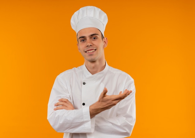Smiling young male cool wearing chef uniform points hand to side with copy space