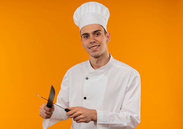 Улыбающийся молодой мужчина круто носить форму шеф-повара точить ножи