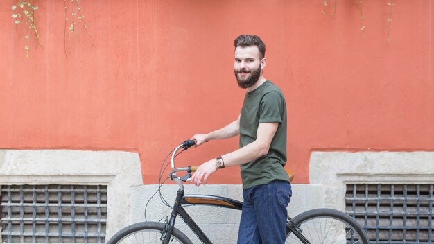 壁の前に自転車で若い男性のサイクリストを笑顔