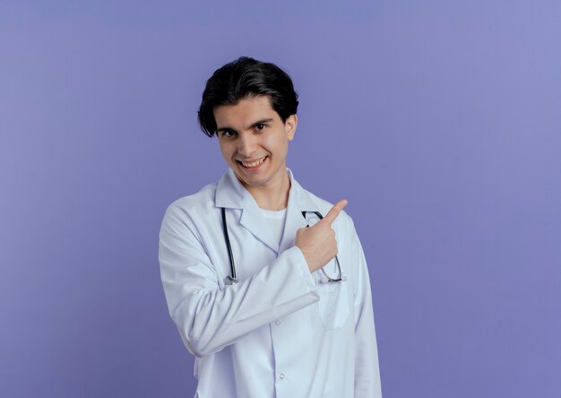 Улыбающийся молодой мужчина-врач в медицинском халате и стетоскопе смотрит за изолированными