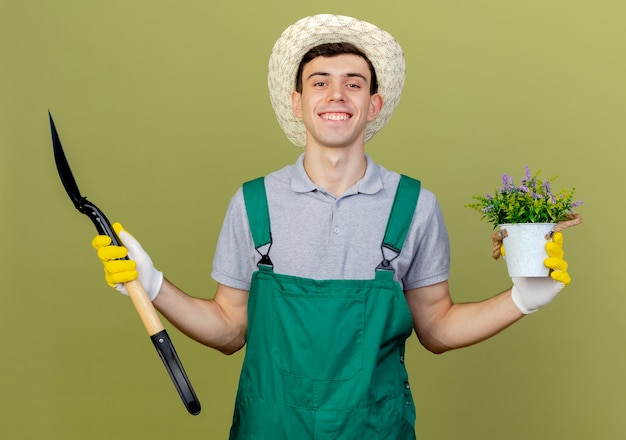 ガーデニングの帽子と手袋を着用して笑顔の若い男性の庭師はスペードを保持します