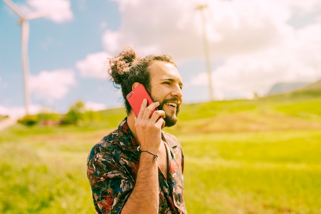 Smiling young male talking on phone in meadow