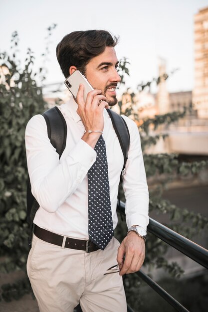 Smiling young male tourist talking on cellphone