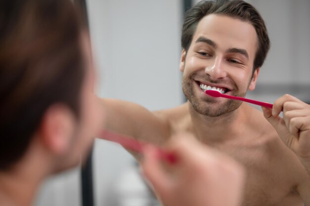 若い男が歯を食いしばって、のんきに見える笑顔