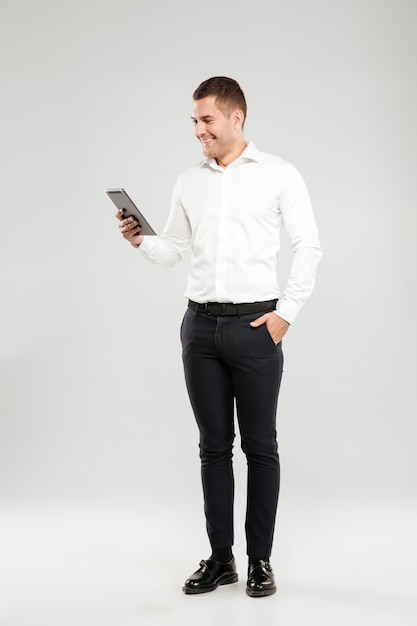 태블릿 컴퓨터로 채팅 웃는 젊은 남자.