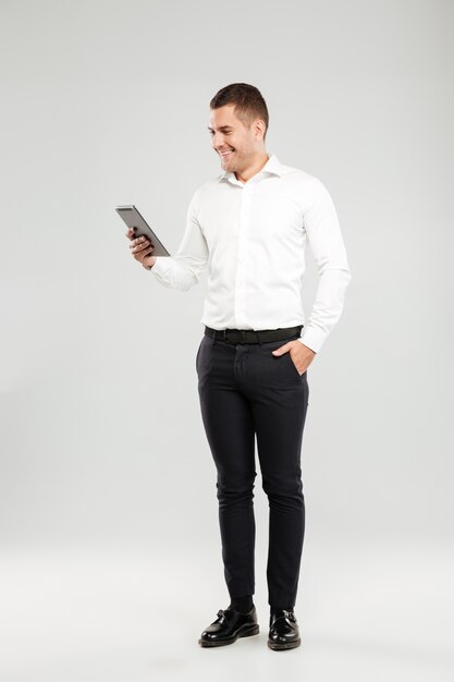 Smiling young man chatting by tablet computer.