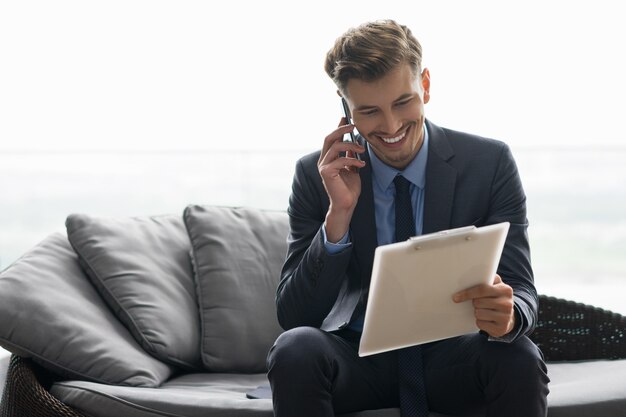 Smiling Young Man Discussing Document on Phone