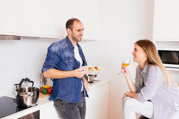 サラダを食べる若い男とアルコールを飲む彼の妻の笑顔