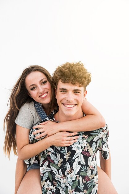 Smiling young man giving piggyback to his girlfriend