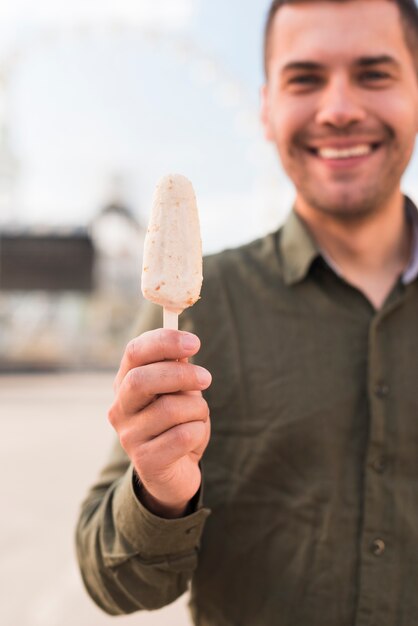 おいしいアイスキャンデーアイスクリームを持って笑顔の若い男