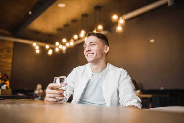 Smiling young man holding glass of drink at restaurant