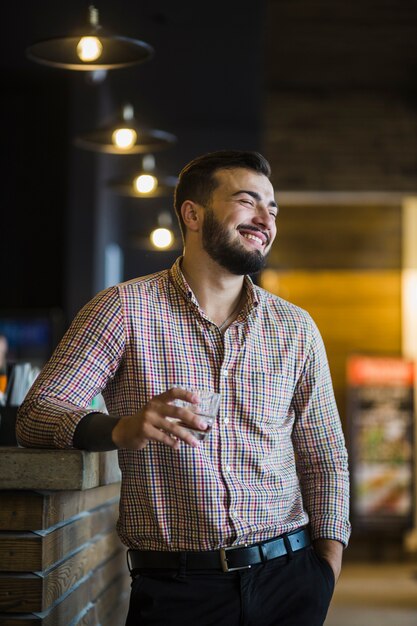 Smiling young man holding glass of drink at restaurant