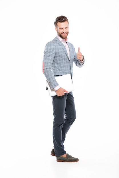 Free photo smiling young man holding laptop showing thumbs up.