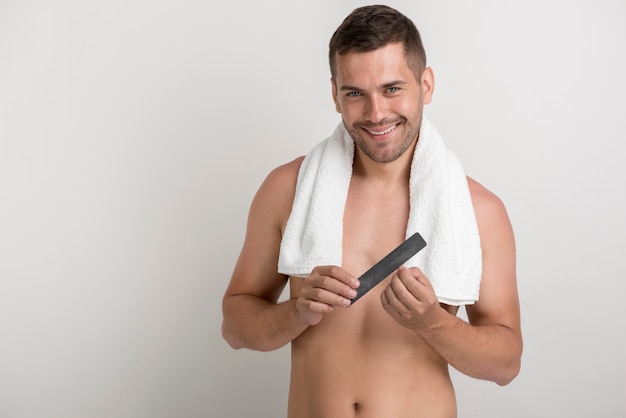 Smiling young man looking at camera while polishing his nails with fine