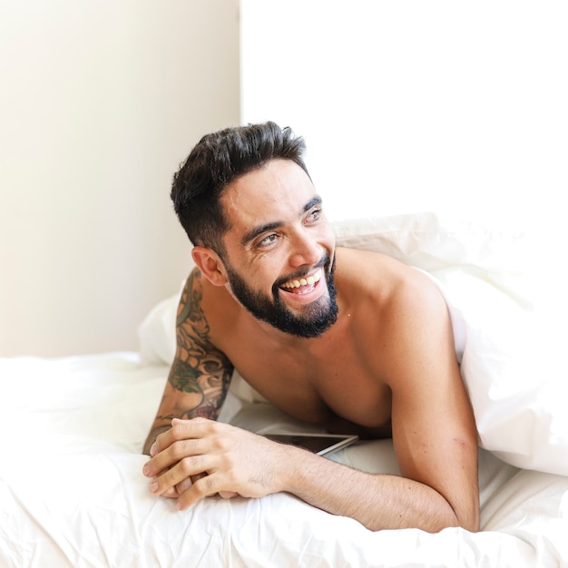 Foto gratuita giovane sorridente sdraiato sul letto