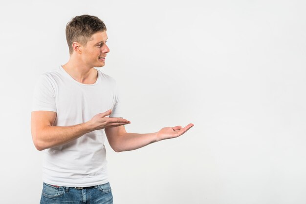 Smiling young man presenting against white backdrop