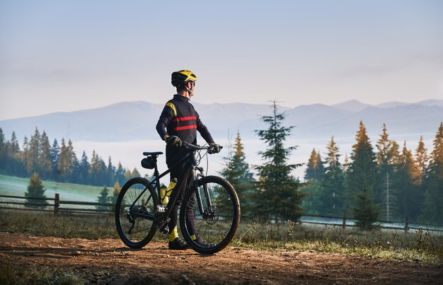 Smiling young man riding bicycle on mountain road