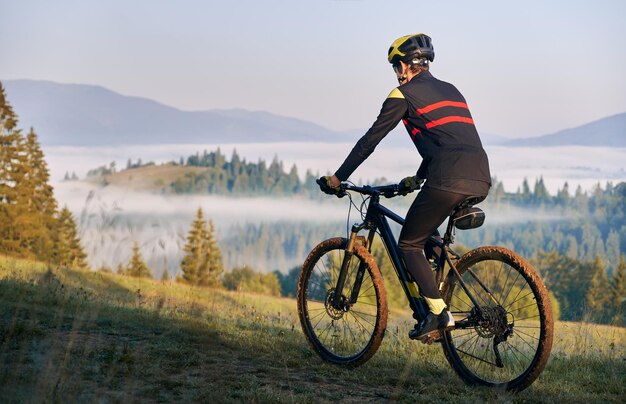 Smiling young man riding bicycle on mountain road