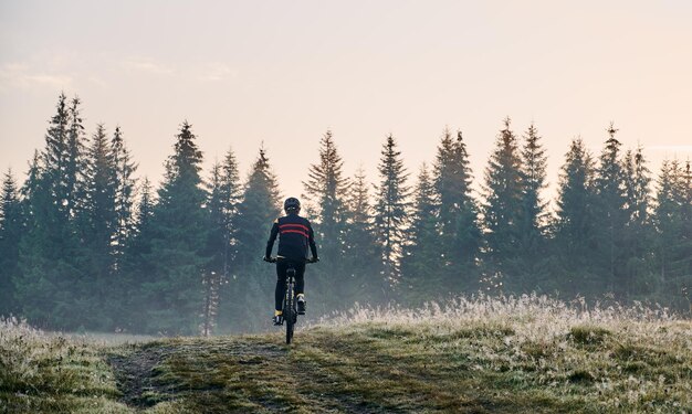 Smiling young man riding bicycle on mountain road