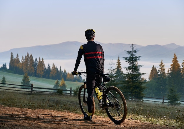 Smiling young man riding bicycle on mountain road