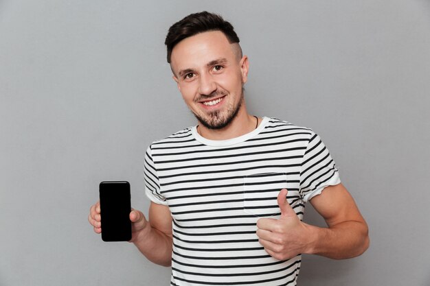 Smiling young man showing display of mobile phone