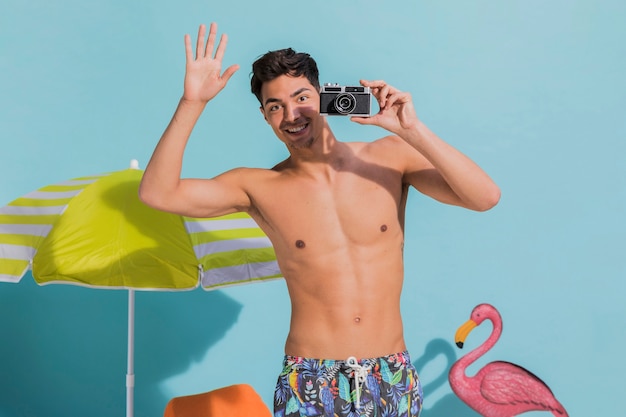 Smiling young man taking photo on camera in studio