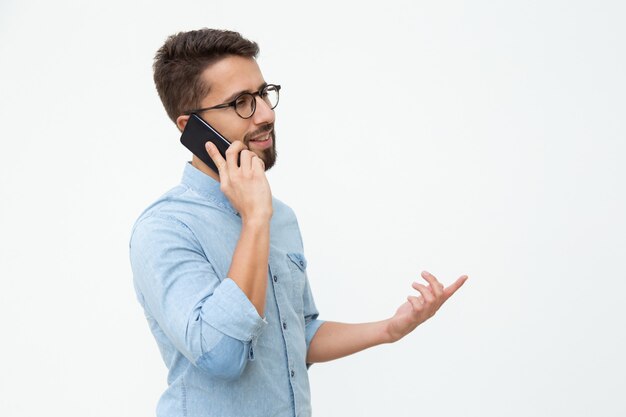 Smiling young man talking by smartphone