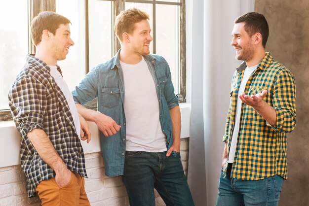 Smiling young man talking to his friends near the window