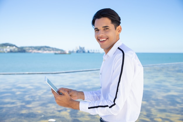 Smiling young man using tablet outdoors