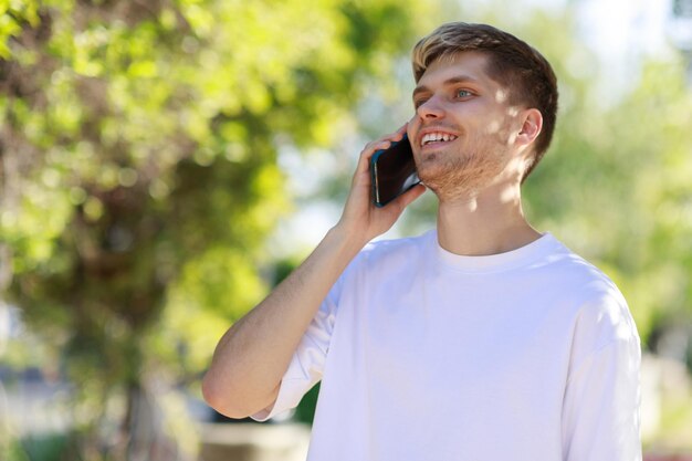 Smiling young man walking at the park at talking on the phone