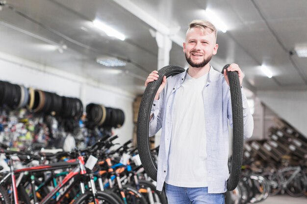 Улыбающийся молодой человек с велосипедными шинами в магазине