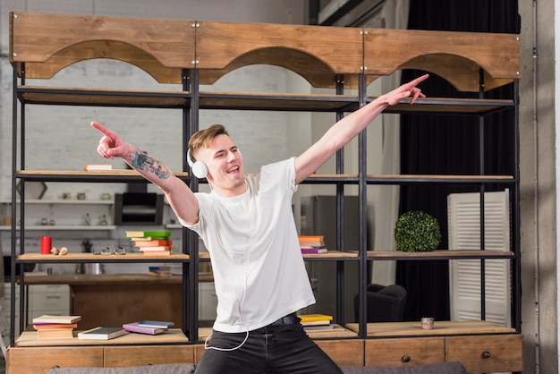 Smiling young man with headphone on his head dancing in front of showcase