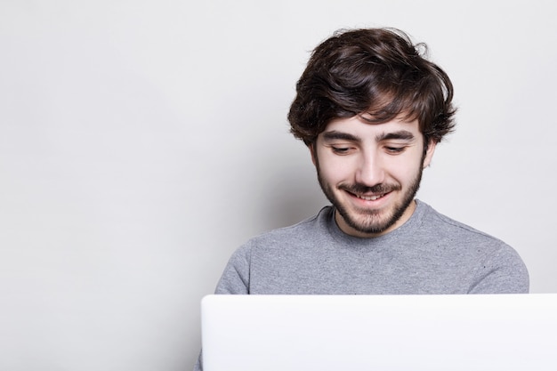 Smiling young man with trendy beard and hairstyle making video call