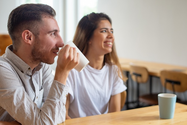 Улыбающийся молодой мужчина и женщина пьют чай в кафе