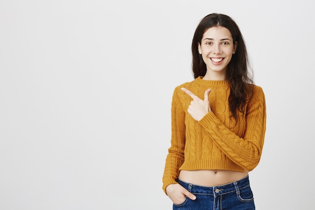 Sorridente giovane ragazza millenaria che punta l'angolo superiore sinistro al tuo logo