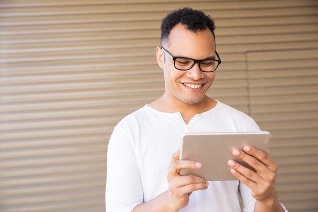 Smiling young mixed-race man working on tablet. Front view