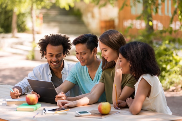 Smiling young multiethnic friends students outdoors using tablet