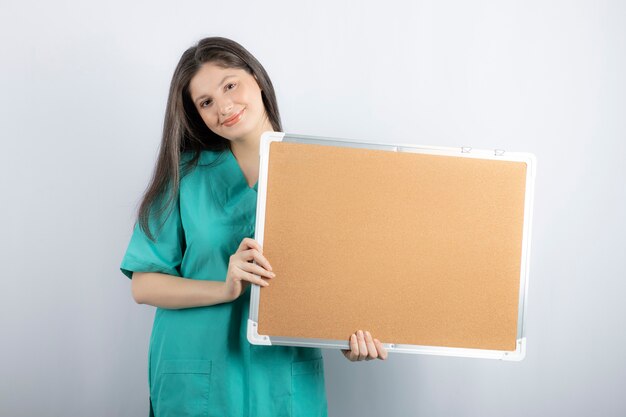 Smiling young nurse holding board with hand.