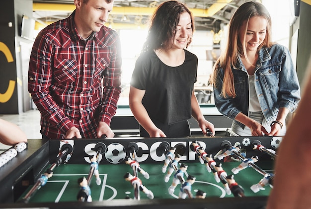 Smiling young people playing table football while indoors