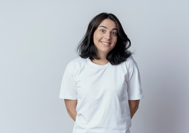 Smiling young pretty caucasian girl keeping hands behind back isolated on white background with copy space