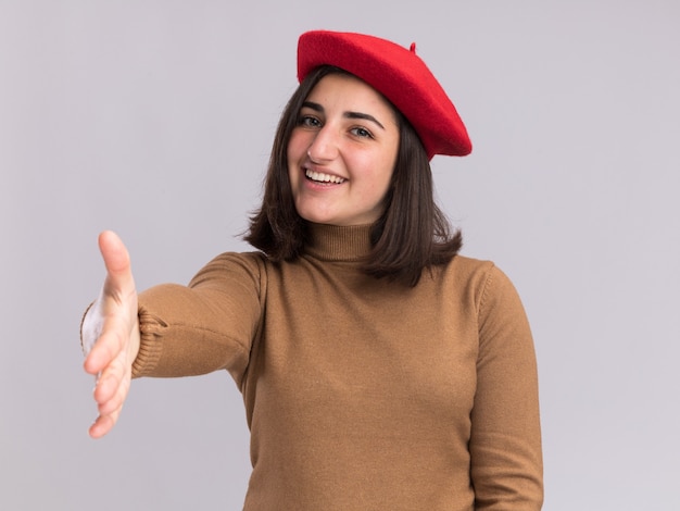 Smiling young pretty caucasian girl with beret hat holding out hand on white